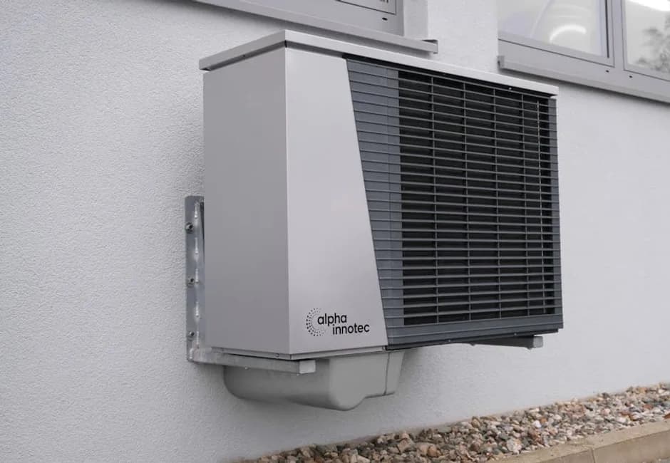 Modern wall-mounted cold-climate heat pump unit on a residential home exterior
