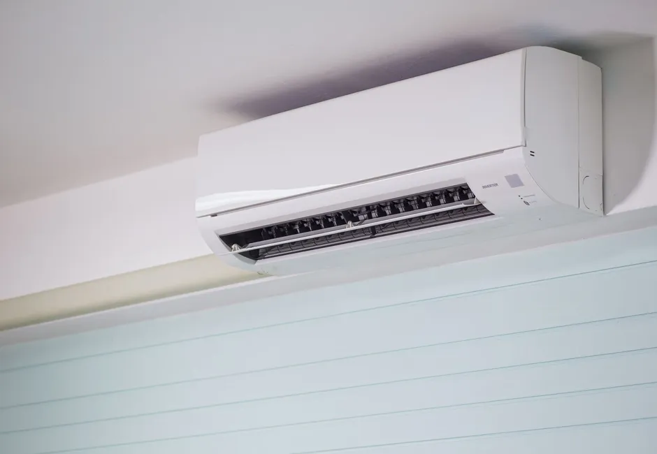 Wall-mounted ductless air conditioner indoor head with its louvres open in a bright room