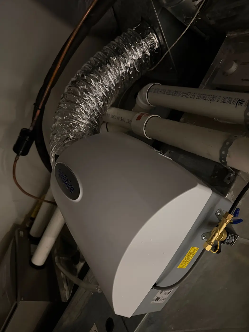AprilAire bypass humidifier mounted on furnace ductwork, with an insulated bypass duct looping to the return and a copper water line feeding the solenoid valve