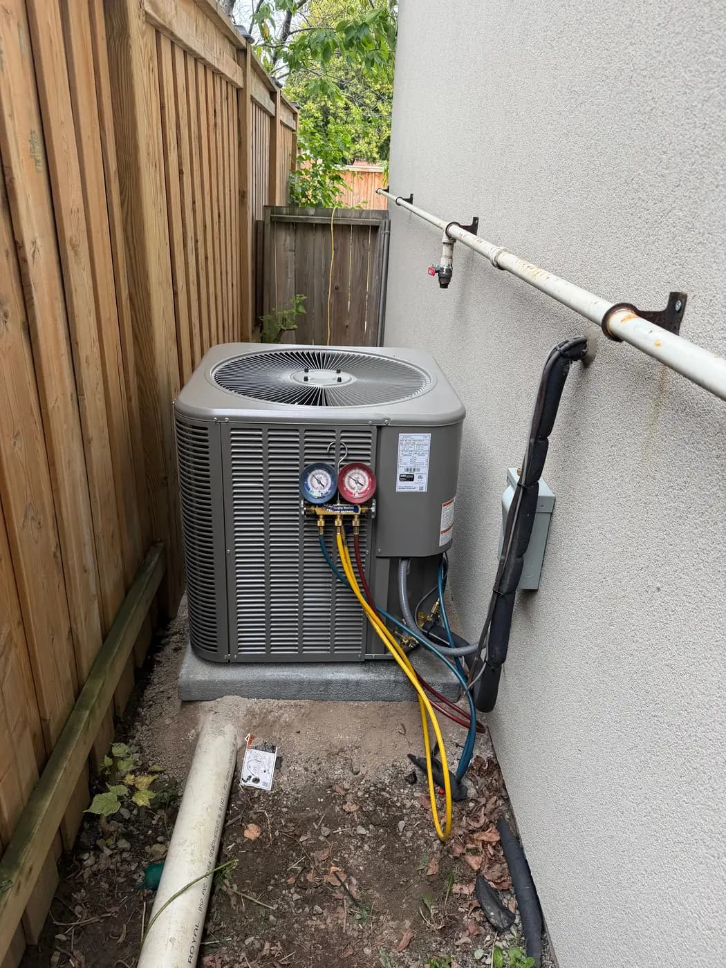 Technician's refrigerant gauges connected to a newly installed Lennox air conditioner during commissioning