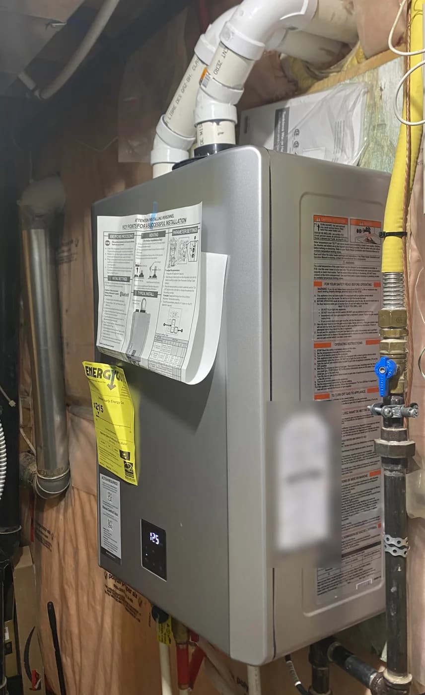 Side view of a Rinnai tankless water heater, with a yellow flexible gas line dropping to a blue-handled shut-off valve on black iron pipe beside the unit